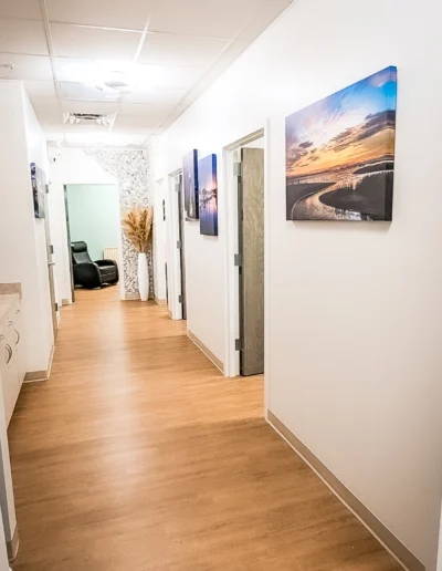 Dovetail Orthopedics hallway with wooden floors, textured wall and vase of pampas grass next to exam room