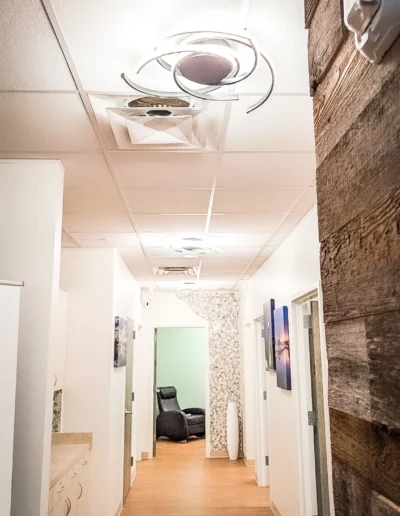 Dovetail Orthopedics hallway leading to exam room, light wooden floors, canvas prints on wall and pebble texture around doorway