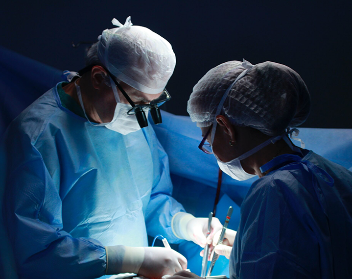 Male surgeon and nurse in action during surgery with a blue background
